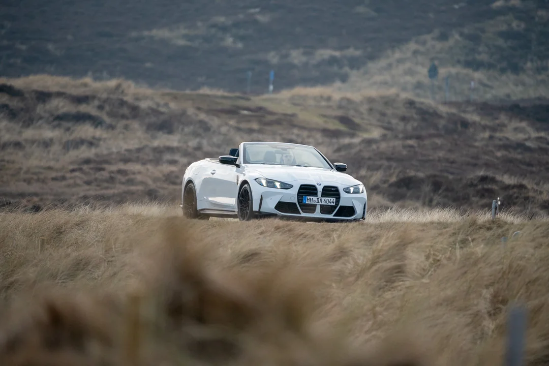 BMW M4 Competition Cabrio in der Sylter Heide- und Dünenlandschaft mit windgeneigtem Strandhafer im Vordergrund